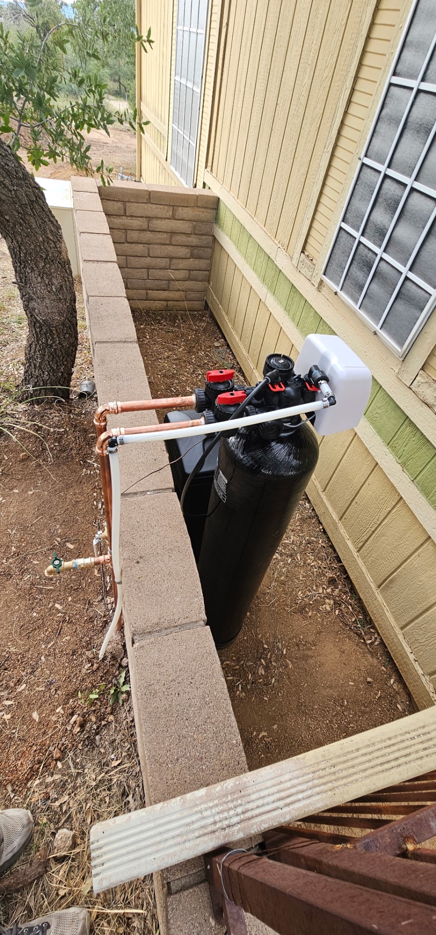 Outdoor softener and filtration system installed beside a block wall in a Tucson side yard
