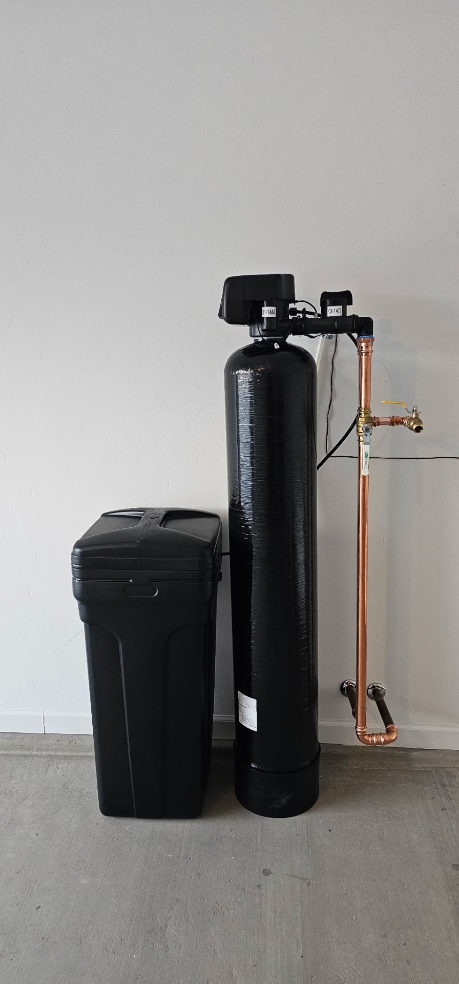 Clean whole-home softener and brine tank install with copper plumbing in a new-build garage